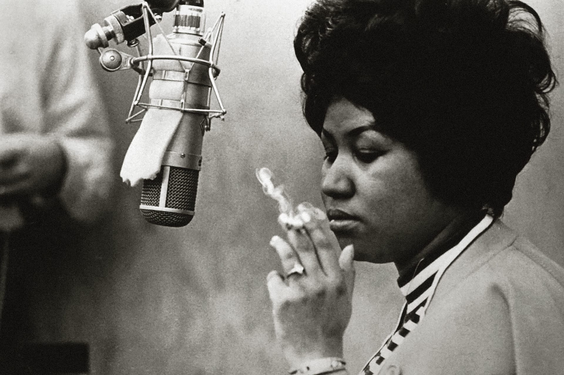 Publicity photo of Aretha Franklin in front of a microphone at a recording studio while smoking a cigarette, circa 1967. File Reference # 32914_999THA